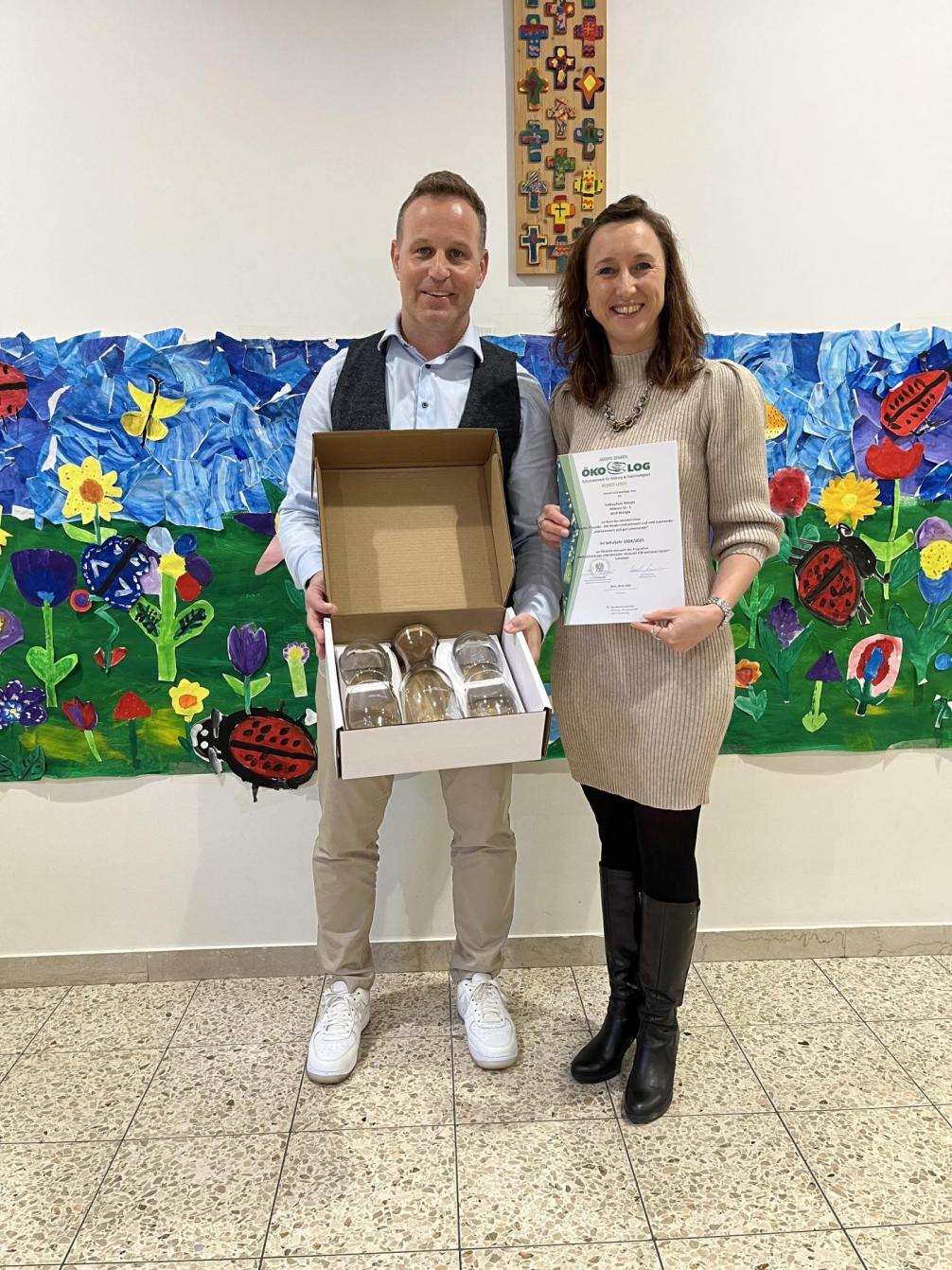 Direktorin hält die Urkunden in den Händen. SQM hält das Geschenk in den Händen 