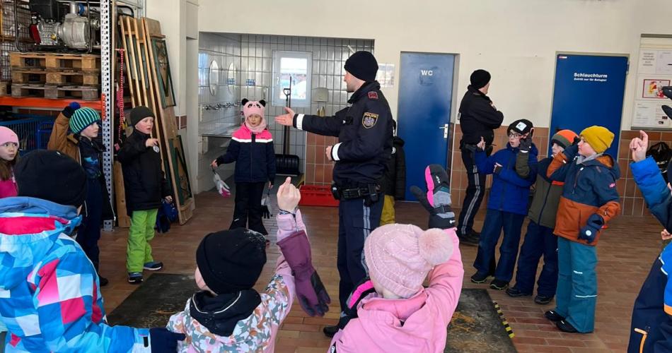 Kinder in der Feuerwehrhalle mit Polizisten 